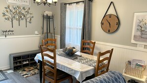 Spisestue med bord, stole, en lysekrone, et ur og et velkommenskilt.