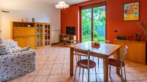 A cozy living room with a sofa, wooden cabinet, and a dining table with chairs. - Sky & Lake by Interhome (Arizzano)