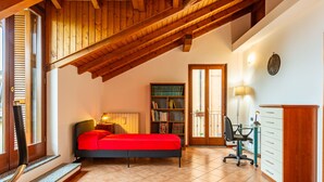 A bedroom with a bed, a desk, a chair, a bookshelf, and a door leading to a balcony. - Sky & Lake by Interhome (Arizzano)