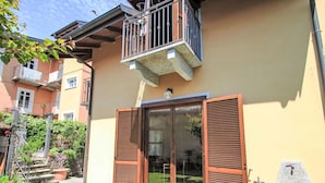 A residential building with a balcony, a sliding glass door, and a stone fountain. - Sky & Lake by Interhome (Arizzano)