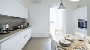A modern kitchen with white cabinets, a built-in oven, and a dining area with a table set for four. - Beautiful private villa for 6 people with WIFI, private pool, A/C, TV and terrace (Marsala)