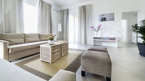 A modern living room with a sofa, ottoman, and coffee table, a white entertainment unit, and a potted plant. - Beautiful private villa for 6 people with WIFI, private pool, A/C, TV and terrace (Marsala)