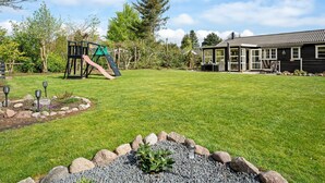 A backyard with a playground, a house, and a well-maintained lawn.