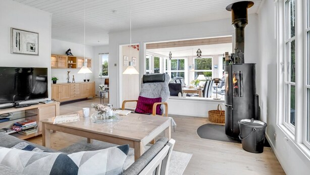 A modern living room with a TV, wooden furniture, a fireplace, and a dining area.