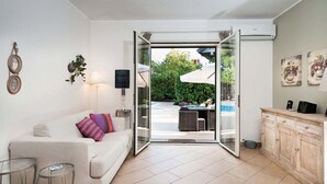 Un salon moderne avec un canapé, une porte vitrée donnant sur une terrasse et un meuble.