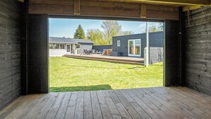 En modern träinredning med en stor glasdörr som leder ut till en uteplats och en trädgård.