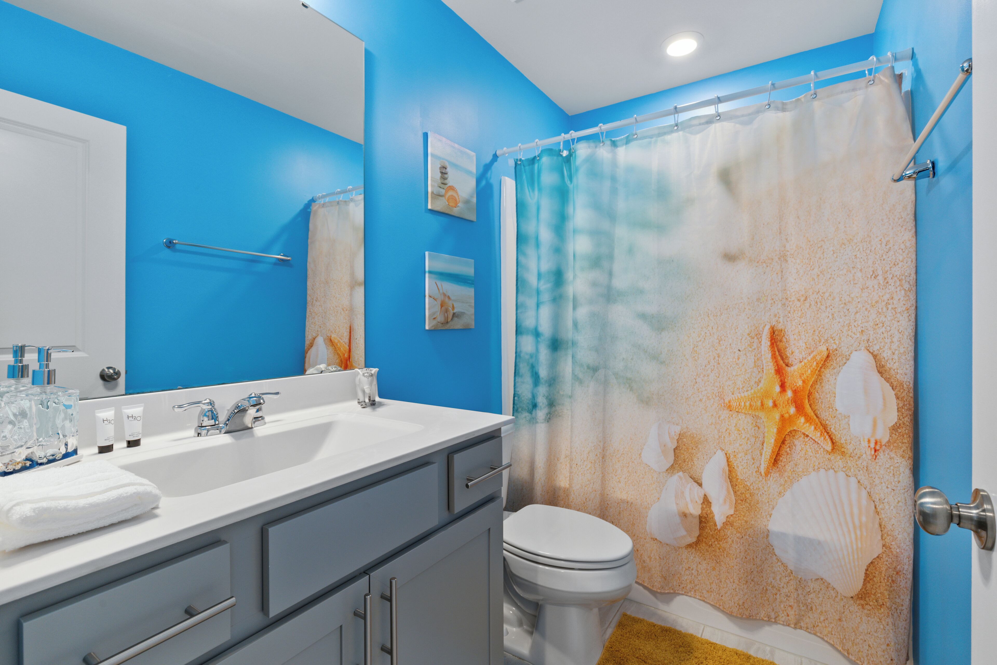 A bathroom with a blue wall, white sink, and a shower curtain with sea-themed designs.