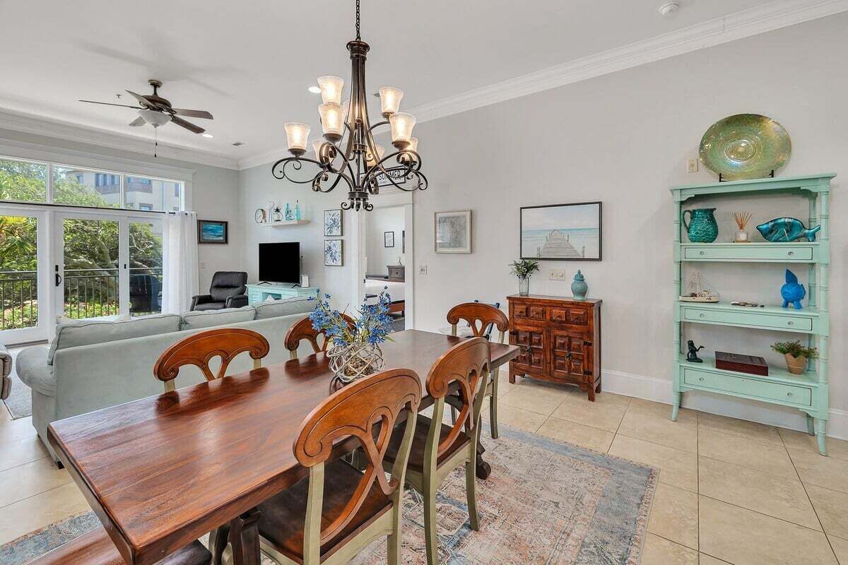 A dining area with a wooden table, chairs, a chandelier, and a teal-colored cabinet with decorative items.