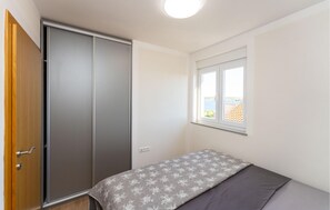 Une chambre à coucher avec un lit, une armoire, une fenêtre donnant sur un beau paysage et un luminaire au plafond.
