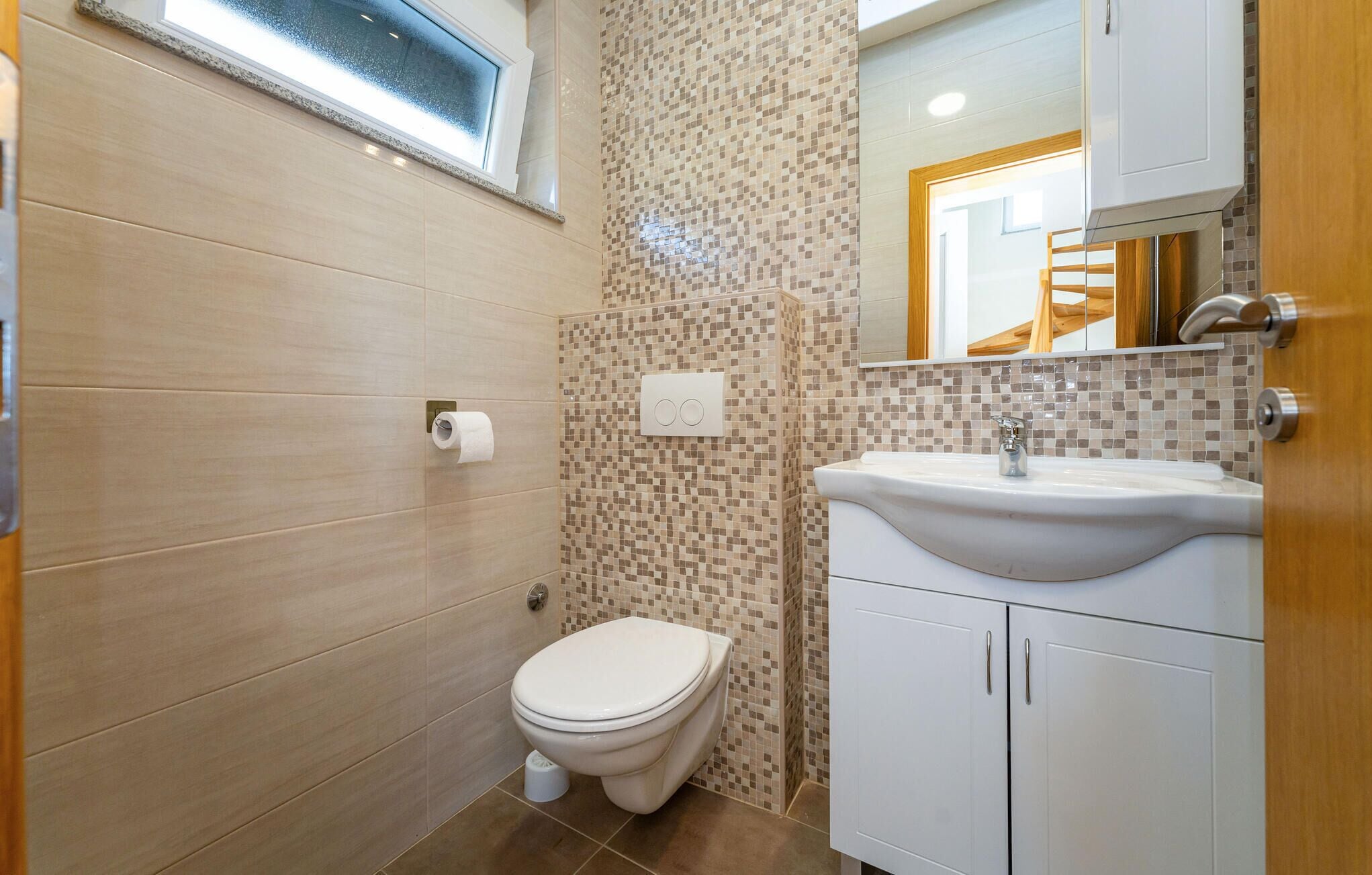A small bathroom with a toilet, sink, and mirror.