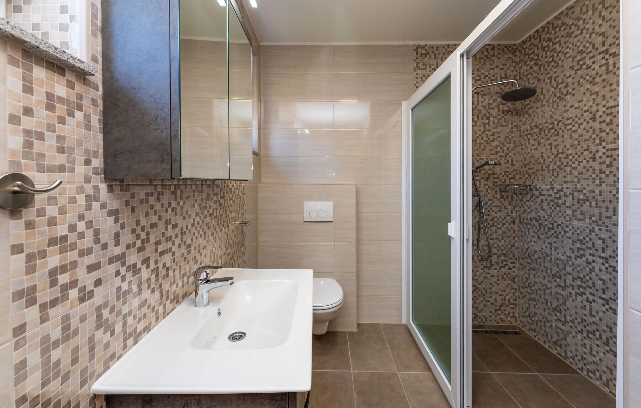 Une salle de bain avec un lavabo blanc, des toilettes et un espace douche.