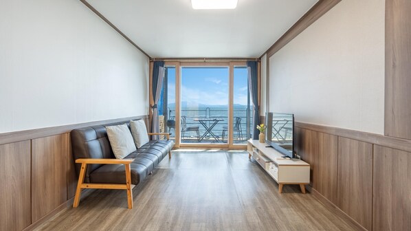 Un salon moderne avec un canapé en cuir, une table basse en bois et un téléviseur posé sur un meuble en bois.