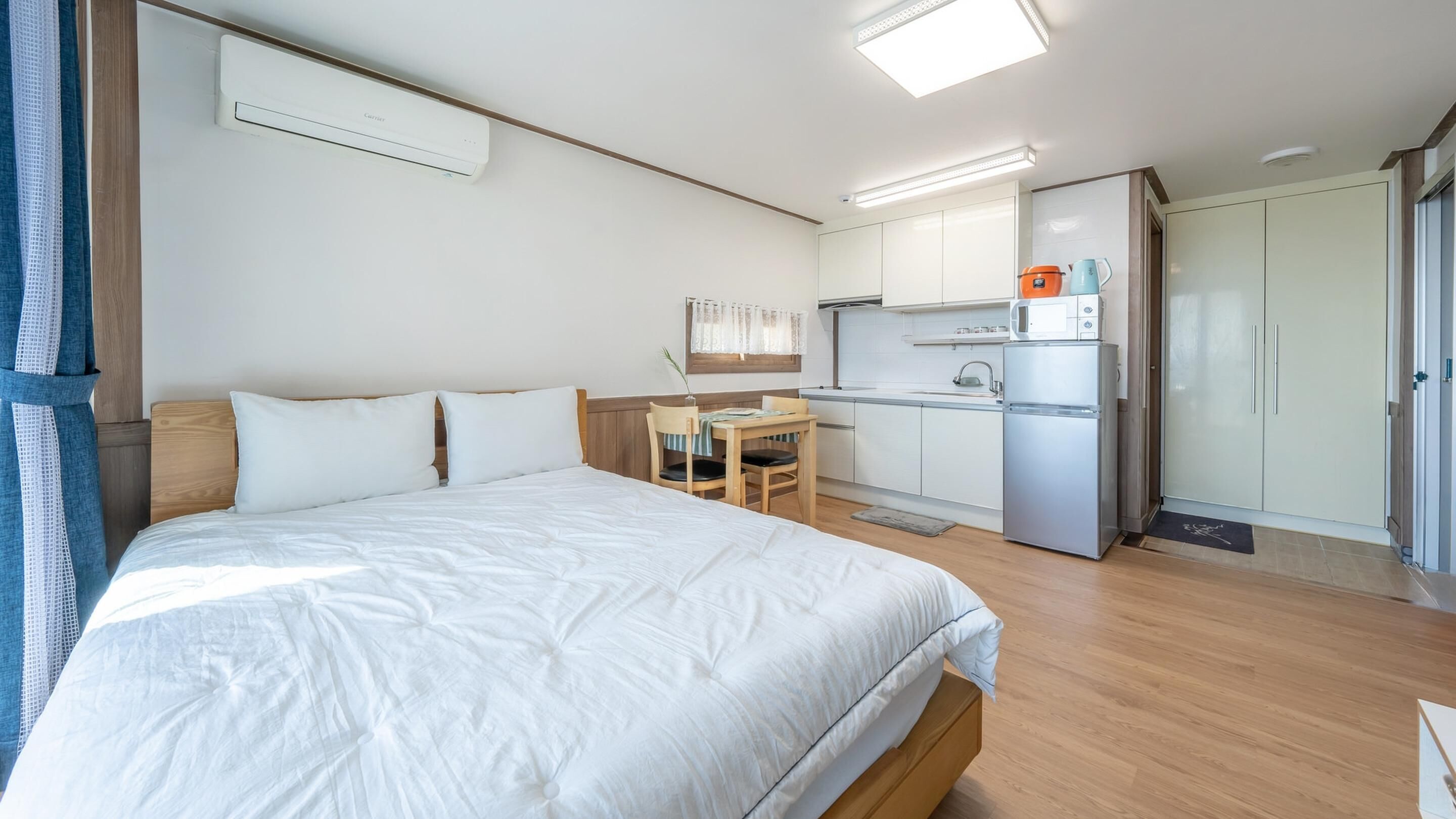 A hotel room with a bed, a small desk, a kitchenette, and a wardrobe.