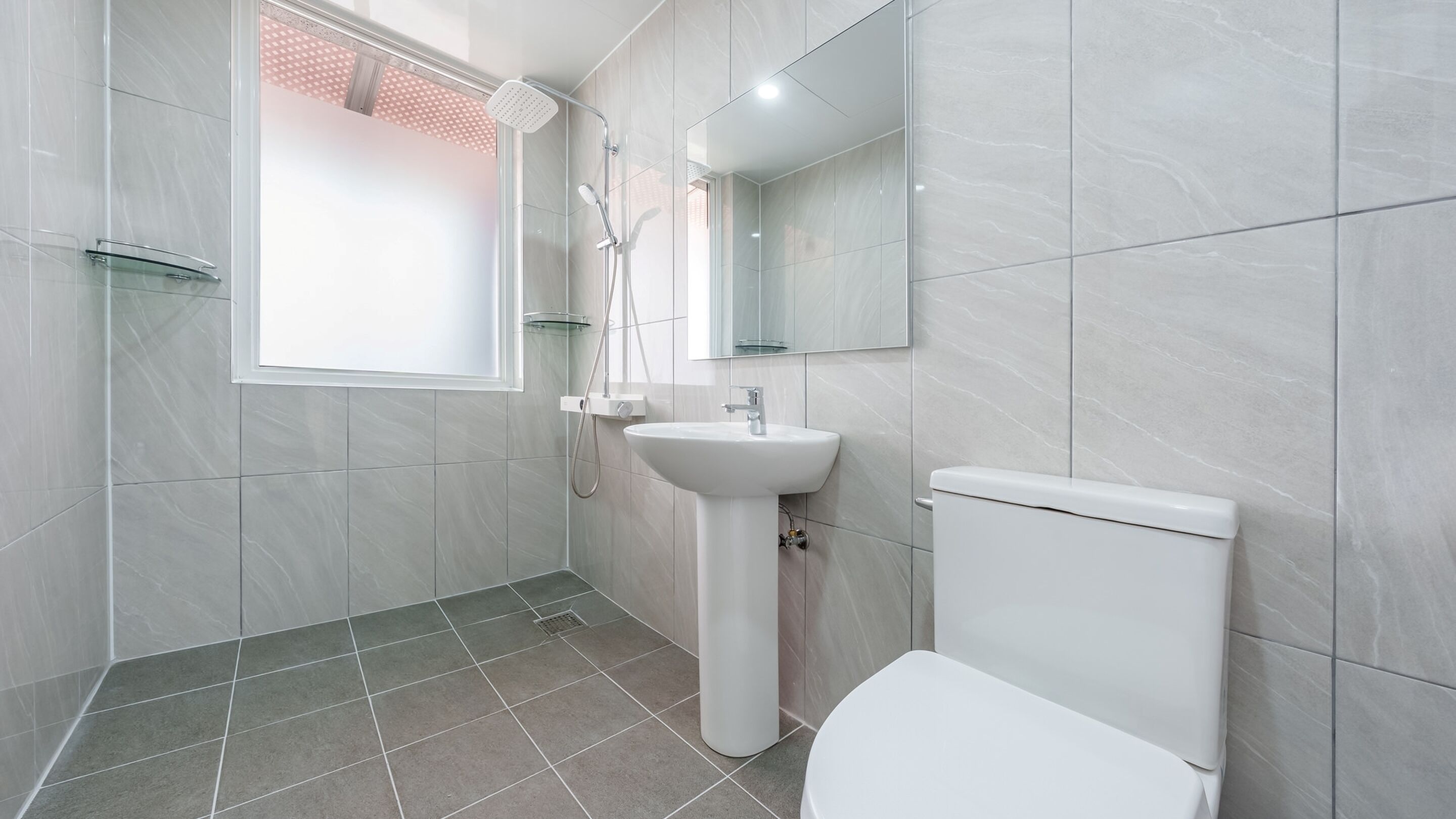 A modern bathroom with a shower, sink, and toilet.