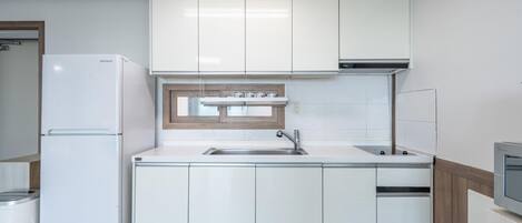 A modern kitchen with white cabinetry, a built-in oven, and a microwave.