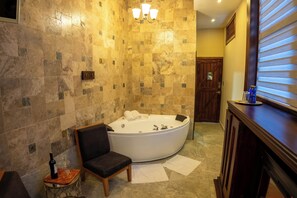 A bathroom with a freestanding bathtub, a chair, a towel rack, and a wooden vanity with a mirror. - QUINTA LOS JUANES (Baños de Agua Santa)
