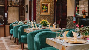 A restaurant with green velvet chairs and marble tables, each set with plates, glasses, and cutlery. - QUINTA LOS JUANES (Baños de Agua Santa)