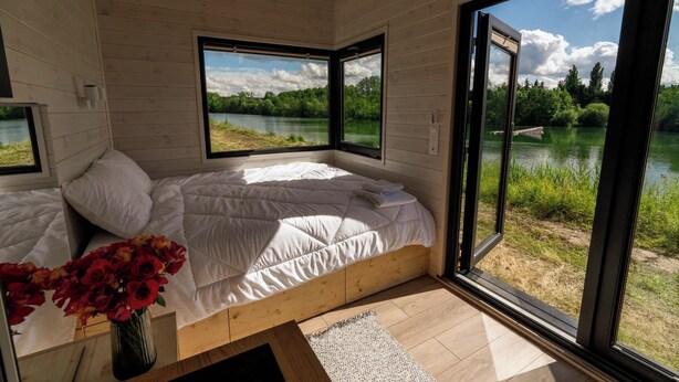 Een slaapkamer met een groot bed, een raam en uitzicht op een meer.