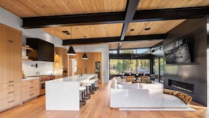 A modern kitchen with a large island, wooden cabinets, and a built-in stove.