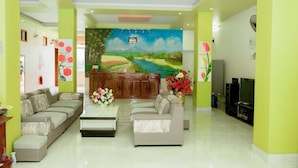 A living room with two sofas, a coffee table, a TV, and a painting of a landscape. - Mami Home - Homestay Lac Village (Mai Ha)