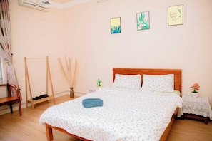 Quarto bem arrumado com uma cama de madeira, uma mesa de cabeceira pequena com luminária e uma cadeira.