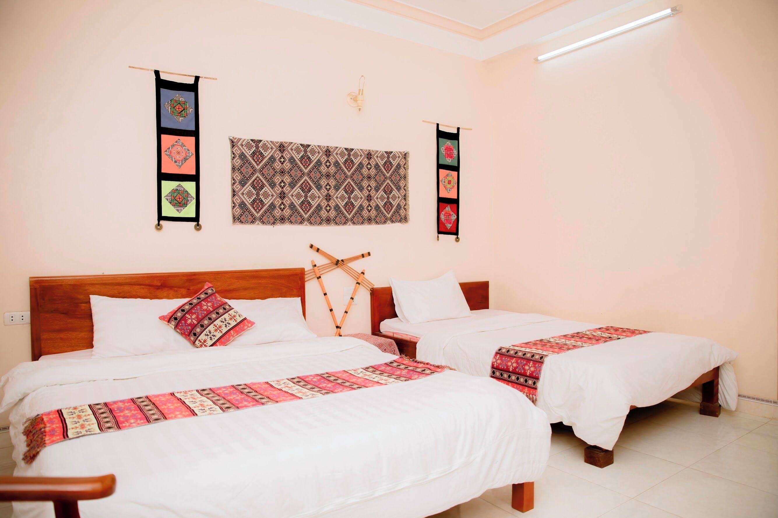 A hotel room with two beds, a large tapestry, and two wall hangings.