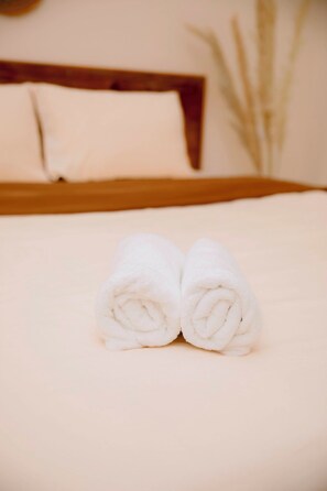Una cama bien tendida con sábanas blancas y un cabecero de madera.