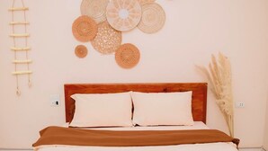 A bedroom with a wooden bed, white bedding, and a wall decorated with circular woven art pieces. - Mami Home - Homestay Lac Village (Mai Ha)