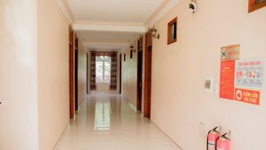 A hallway with a tiled floor, doors on both sides, and fire safety signs on the right wall. - Mami Home - Homestay Lac Village (Mai Ha)