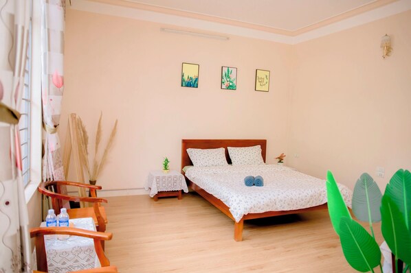 Un dormitorio con una cama de madera, una mesita de noche pequeña y una ventana con cortinas.