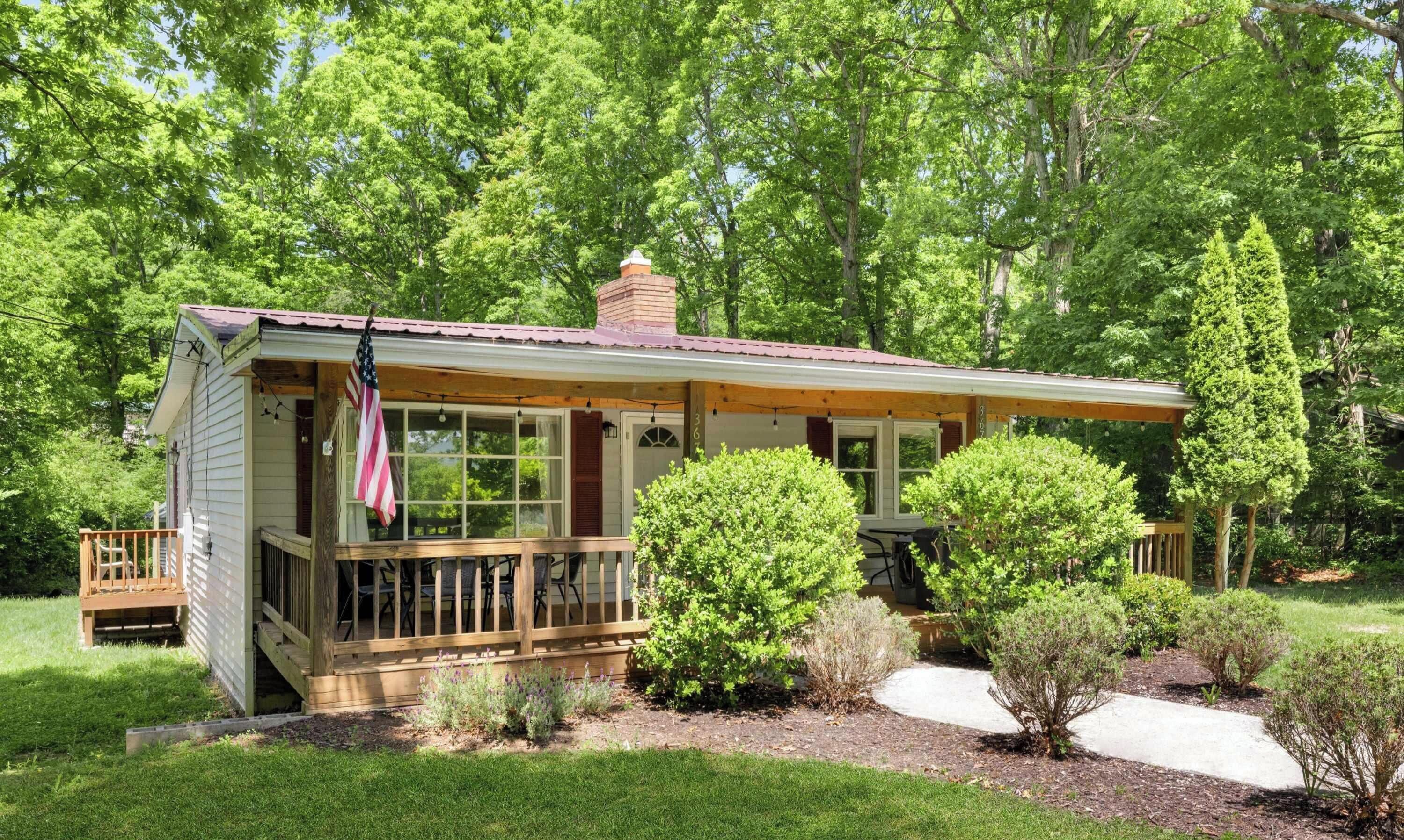A single-story house with a porch, a chimney, and a flag.