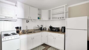 Une cuisine avec des meubles blancs, une cuisinière, un four à micro-ondes et un réfrigérateur.