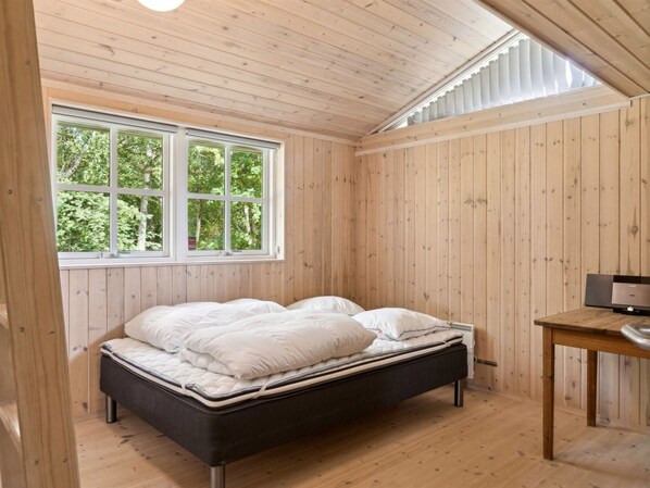 A bedroom with a bed, a window, and a desk.