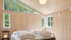 Une chambre à coucher avec un lit, une chaise et de grandes fenêtres.