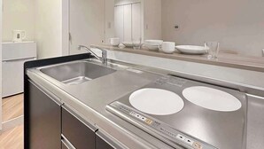 A modern kitchen with a stainless steel sink, a built-in oven, and a large mirror above the counter. - Breakfast & Comfort in Hiroshima's Heart (Naka Ward, Hiroshima)