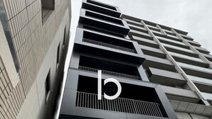 A modern building with a prominent 'b' logo on the facade, featuring a geometric design with balconies and a flat roof. - Breakfast & Comfort in Hiroshima's Heart (Naka Ward, Hiroshima)