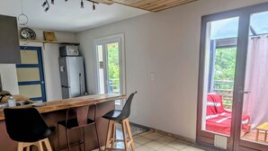 Una cocina compacta con mostrador de madera, dos taburetes de bar y un refrigerador.
