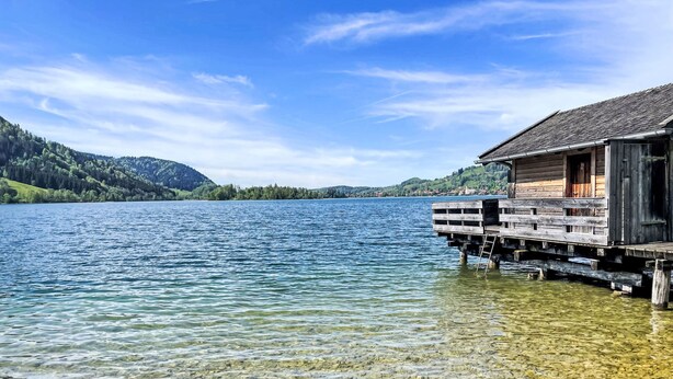 A wooden cabin on stilts over clear water, surrounded by hills and a clear sky. - Tiny Haus Glockenalm-Hopfen Hütte by Interhome (Fischbachau - Schliersee)