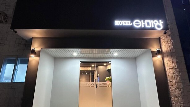 L’entrée d’un hôtel, dotée d’un design moderne, avec un comptoir d’accueil et une enseigne au-dessus de la porte.