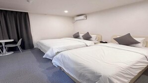 Une chambre d’hôtel avec deux lits simples, une petite table et une chaise.