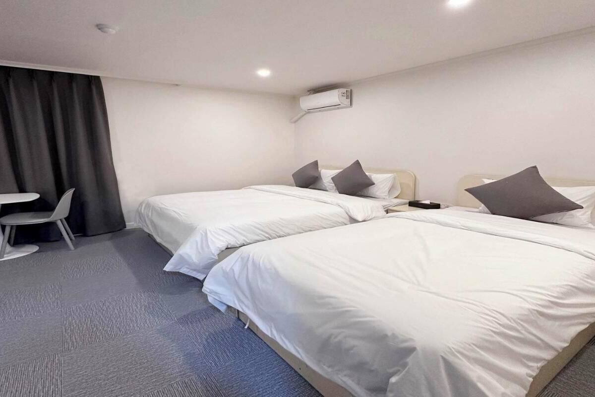 Une chambre d’hôtel avec deux lits simples, une petite table et une chaise.