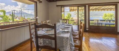 Un coin repas avec une table dressée pour quatre personnes, de grandes fenêtres donnant sur un lac et des montagnes, et un plancher en bois.