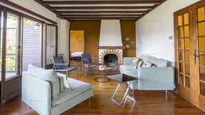 Een gezellige woonkamer met een open haard, houten vloeren en comfortabele zithoek.