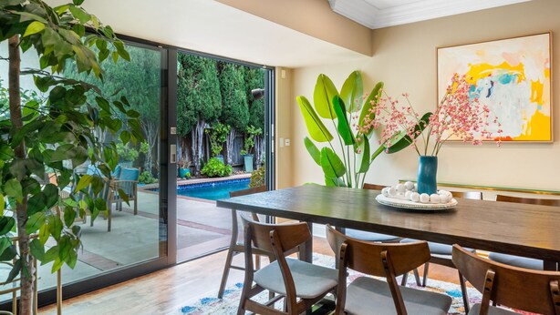 A dining area with a large table, chairs, and a view of a swimming pool and greenery outside. - 6BR Villa with Pool, Jacuzzi & Game Room, Walk to Rodeo Drive (Los Angeles)