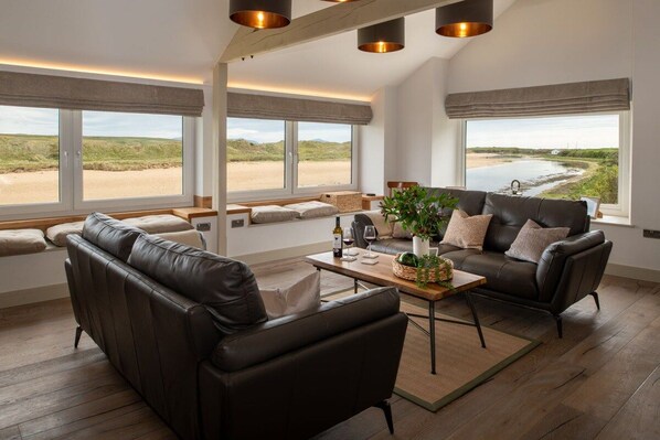Un salón moderno con sofá, mesa de centro y vista al mar.
