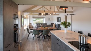 Een moderne keuken met een groot eiland, inbouwapparatuur en een eetgedeelte met uitzicht.