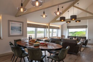 A spacious dining area with a round table, multiple chairs, and pendant lighting.