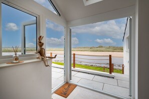 Habitación con vista a la playa y dunas, felpudo y una figura decorativa de conejo.