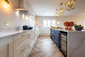 Una cocina moderna con armarios blancos, horno empotrado e iluminación colgante.