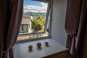 A window with a view of houses and a tree, and three decorative balls on the sill. - No. 66: Stylish Pet-Friendly Cottage in Beaumaris (Beaumaris)